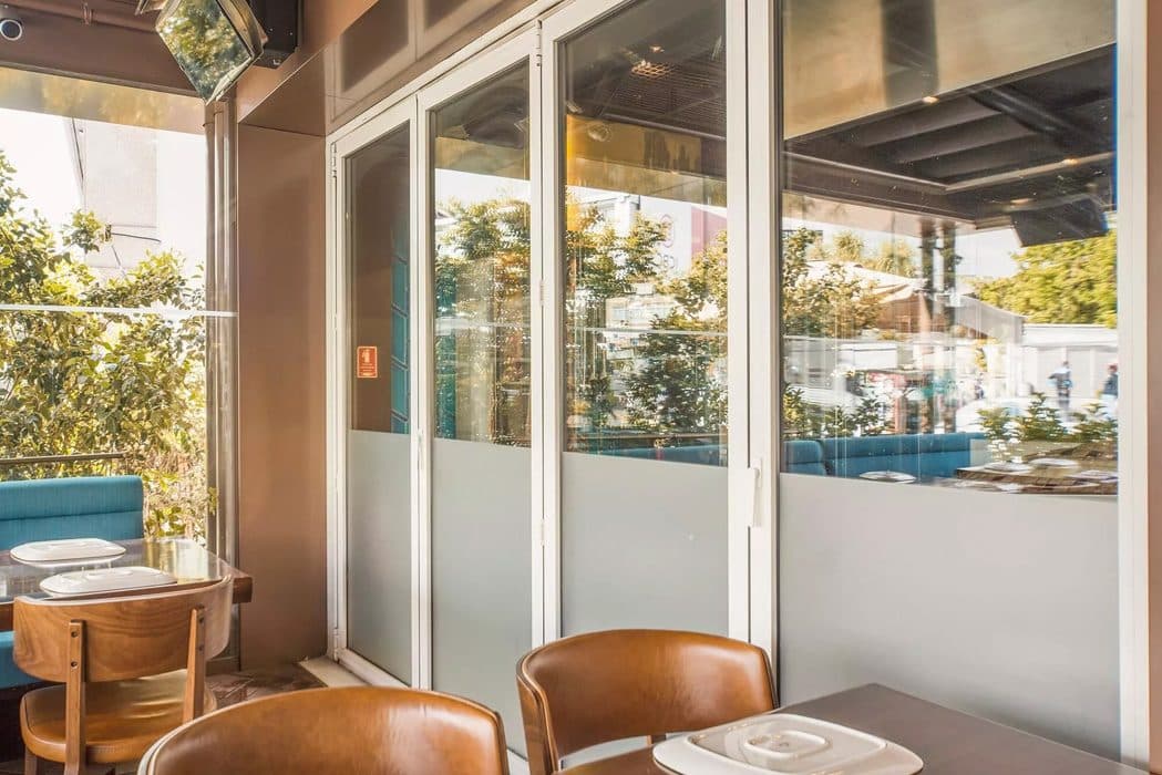 Restaurant met leren stoelen achter een glazen vouwwand met matglas aan de onderkant