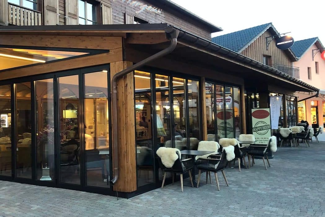 Houten horecapand met zwarte glazen vouwwanden rondom een overdekt terras