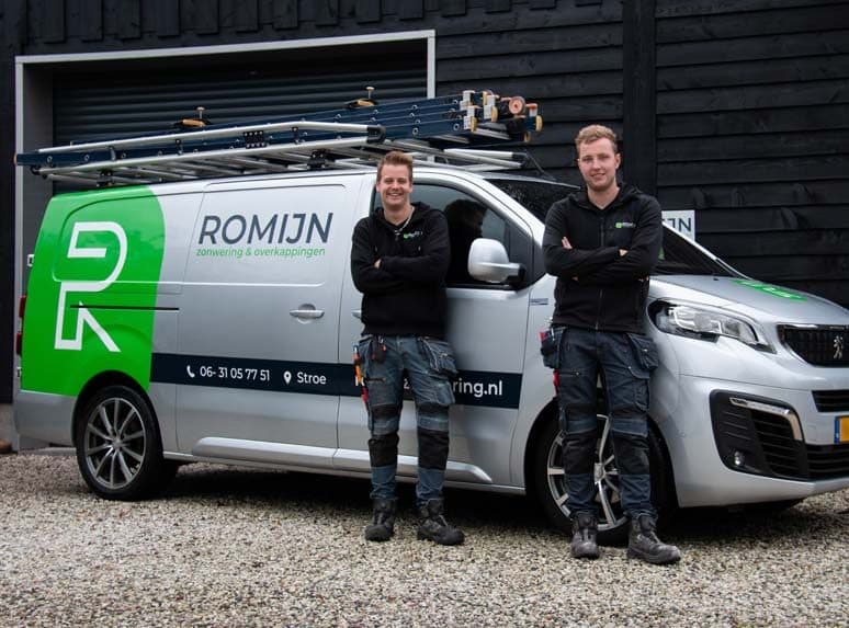 Twee medewerkers van Romijn bij de bedrijfsbus met ladders op het dak