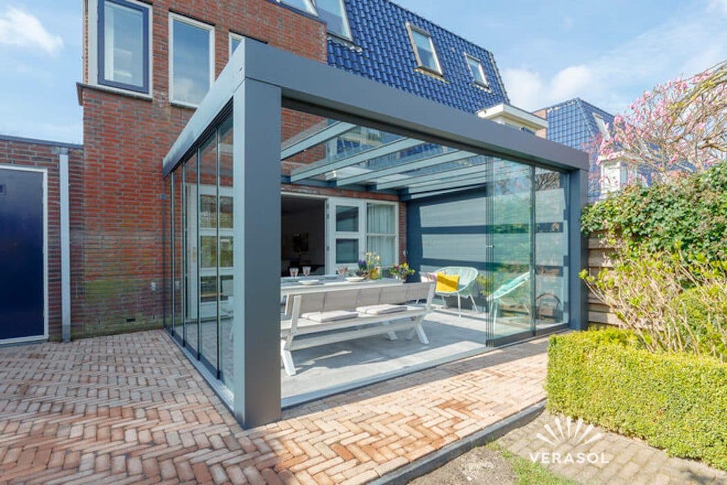 Antraciet veranda met kubusvormig kader en glazen schuifwanden naast een rijwoning, schuin van opzij