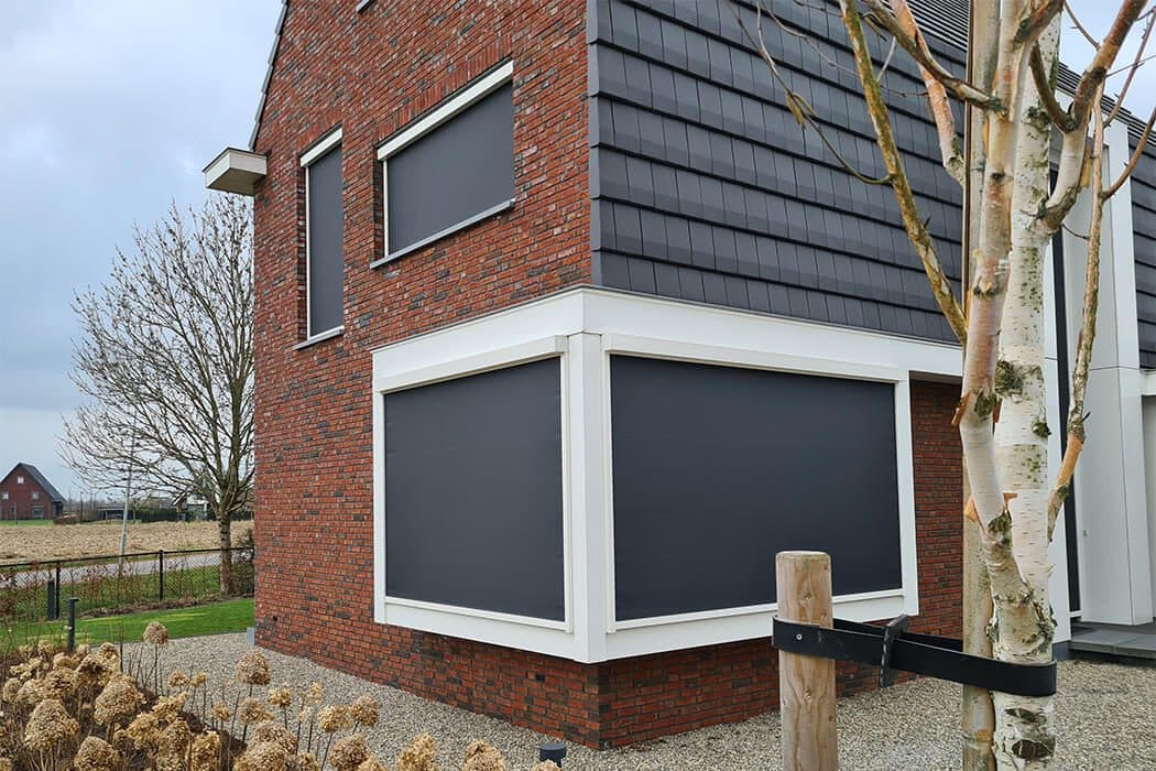 Antraciet screens voor een erker en een raam van een roodbakstenen woning